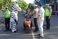 Kasat Lantas Polresta Pati, Kompol Asfauri memberikan helm anak berstandar SNI di kawasan Alun-alun Pati. Foto: Istimewa 